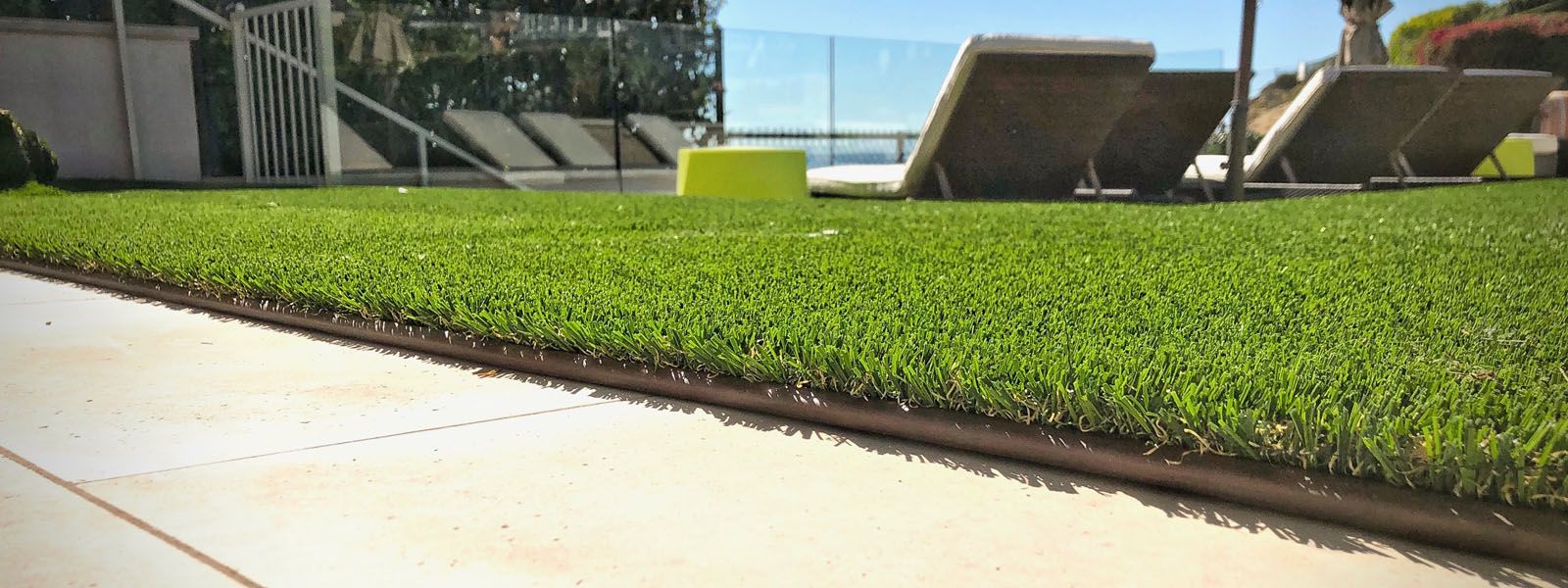 brown artificial turf edging against tan tiles